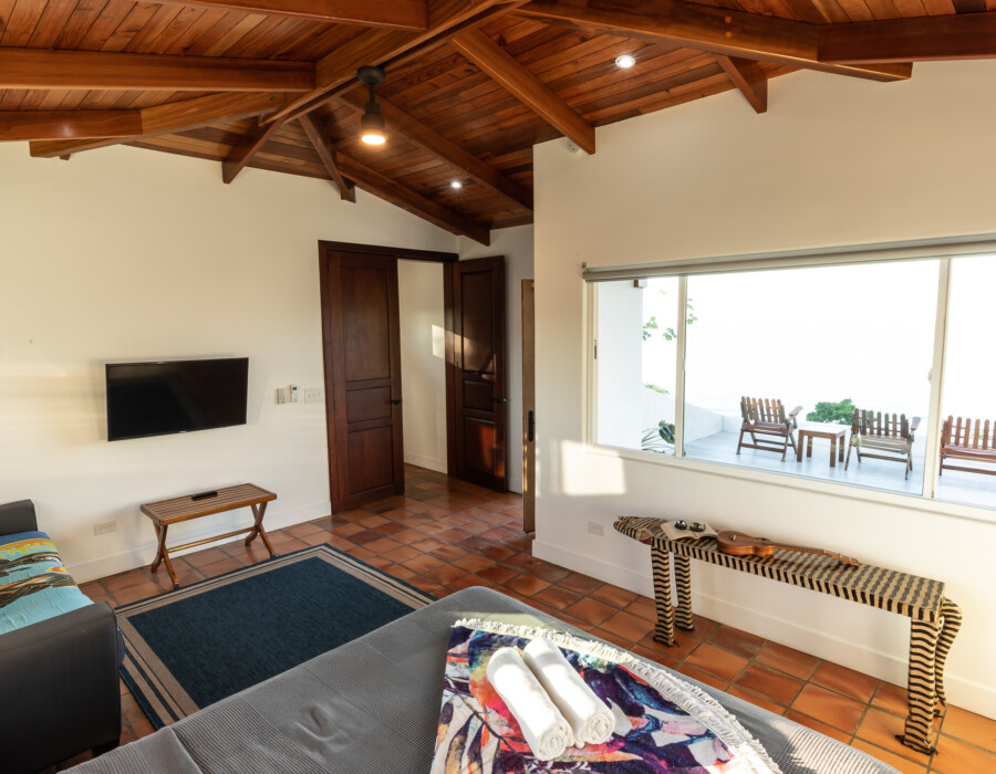 Large room with double bed, tv and sofa and balcony with sea view. Casa Colby